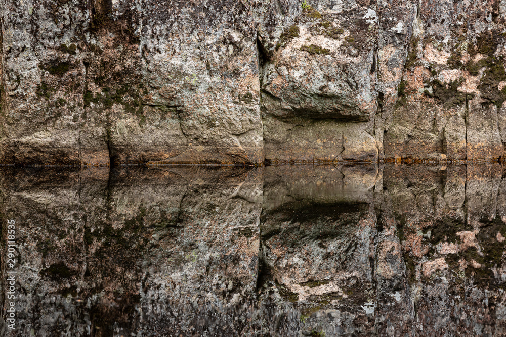 Rock reflectin to still water in forest lake Rock reflectin to still water in forest lake