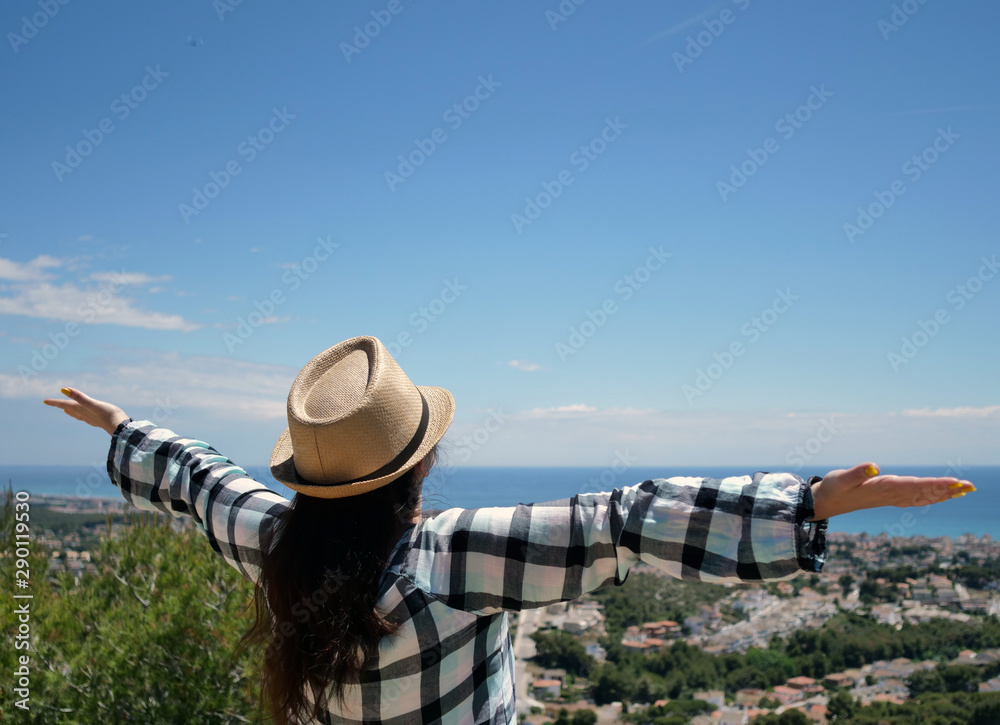 Attractive girl tourist in a hat stands on the mountain, spreading her arms wide apart, enjoying the journey, freedom Attractive girl tourist in a hat stands on the mountain, spreading her arms wide apart, enjoying the journey, freedom