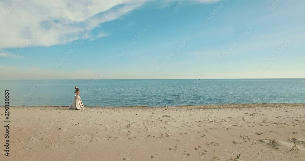 Aerial view from drone of wedding couple walking at the beach. Wedding day. Newlyweds, bride and groom near the picturesque blue ocean Aerial view from drone of wedding couple walking at the beach. Wedding day. Newlyweds, bride and groom near the picturesque blue ocean