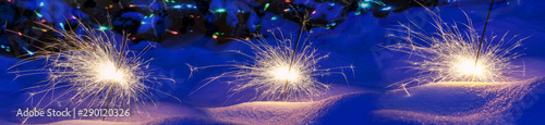 Festive background. Bengal fire, fireworks, spark, snow, bokeh effect. Christmas or New Year. Selective focus, close-up.