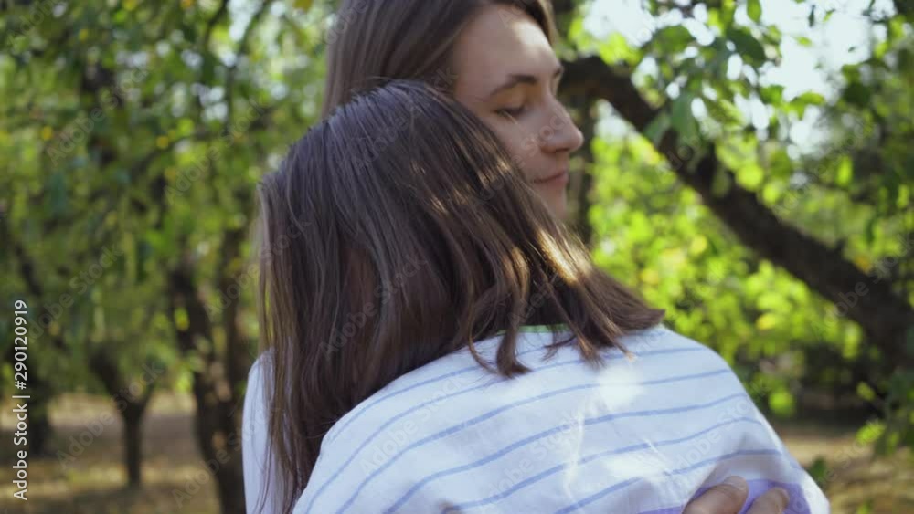 Happy young man and woman hugging and smiling happily while standing in park or garden. Leisure outdoors, connecting with nature. Camera moving around Happy young man and woman hugging and smiling happily while standing in park or garden. Leisure outdoors, connecting with nature. Camera moving around