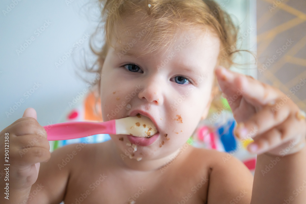 Happy funny Little asian girl eating breakfast and she holding spoon in her hands Happy funny Little asian girl eating breakfast and she holding spoon in her hands