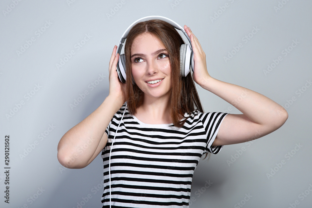 Young beautiful woman with headphones on grey background Young beautiful woman with headphones on grey background