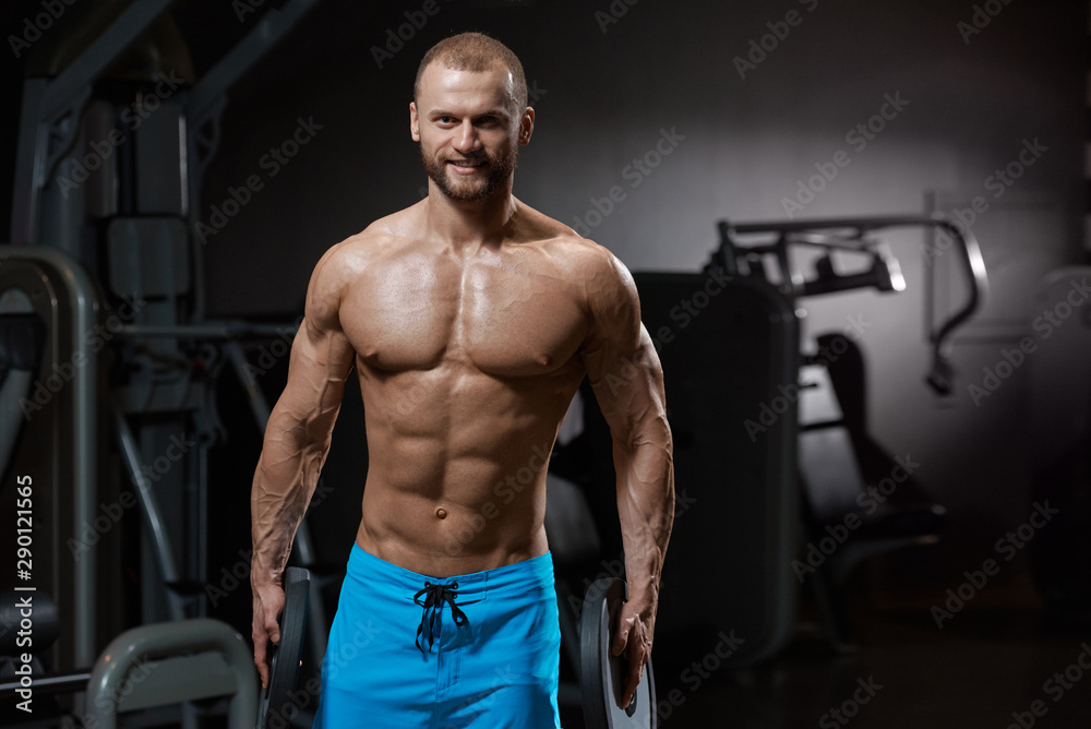 Portrait of strong smiling muscular bodybuilder holding barbell weights in both hands Portrait of strong smiling muscular bodybuilder holding barbell weights in both hands