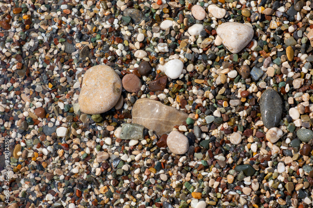 Thin white foam and the many small bubbles on the glittering sea water with the colorful pebbles underneath Thin white foam and the many small bubbles on the glittering sea water with the colorful pebbles underneath