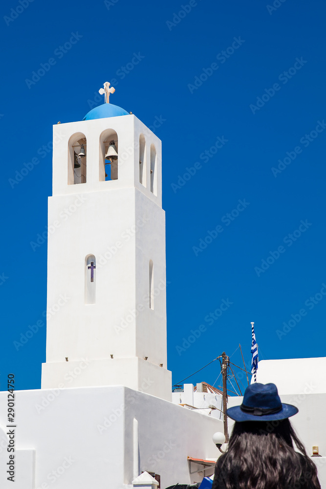 Girl  looking at the bell tower of the parish church of St. Gerasimos located in Fira of Santorini