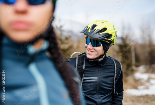 Two mountain bikers standing on road outdoors in winter.
