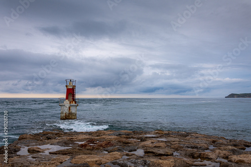 Seascape with a lighthouse on a cloudy afternoon on the coast of Cantabria, Spain