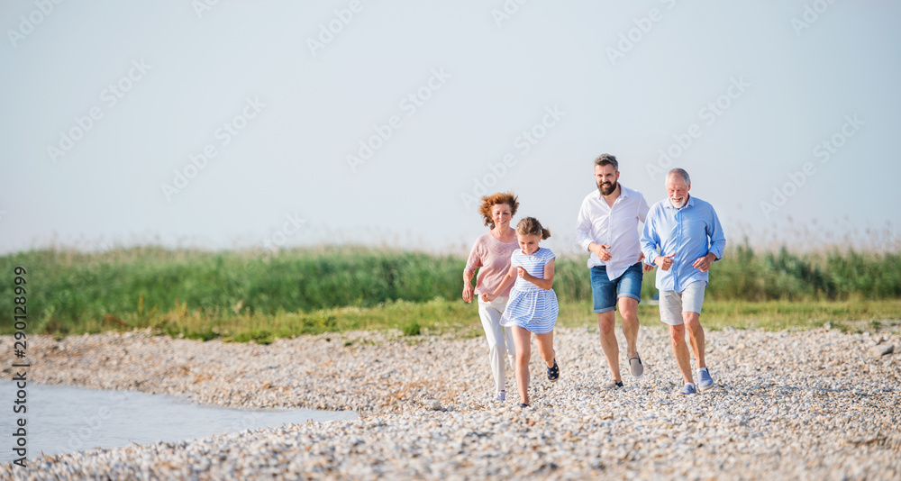 Multigeneration family on a holiday on walk by the lake, running.
