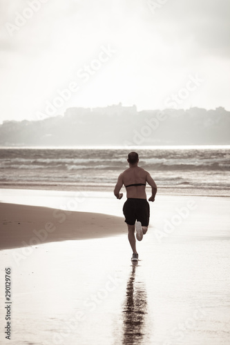 Fitness sports man using heart rate monitor running on beach