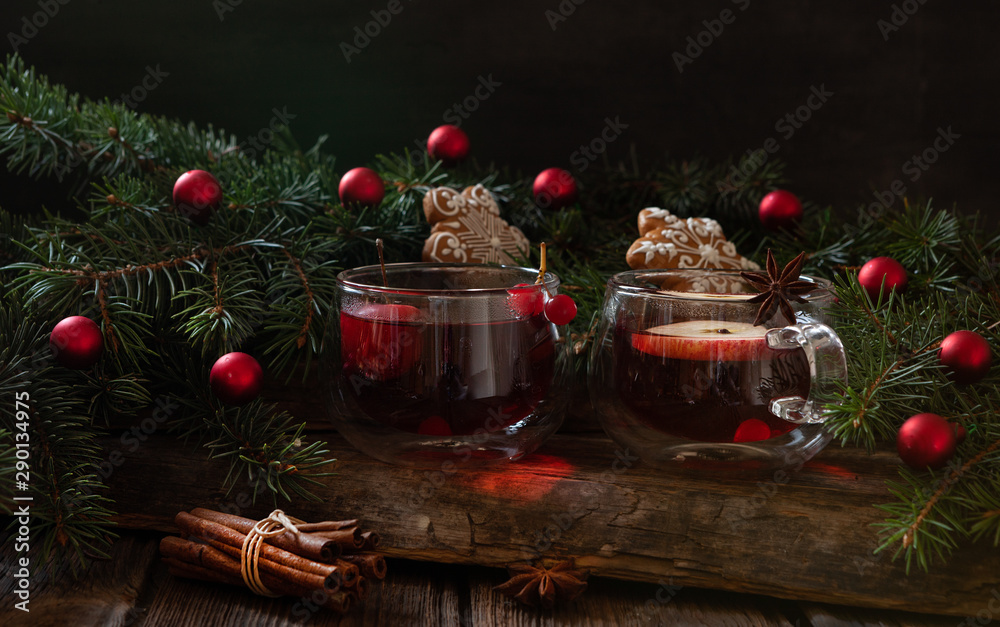 Two red cups with hot fruit drink gingerbread. Christmas concept with fir tree branches. Close-up, selective focus, shallow depth of field Two red cups with hot fruit drink gingerbread. Christmas concept with fir tree branches. Close-up, selective focus, shallow depth of field