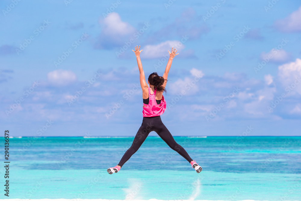 Fit young woman doing exercises on tropical white beach in her sportswear Fit young woman doing exercises on tropical white beach in her sportswear