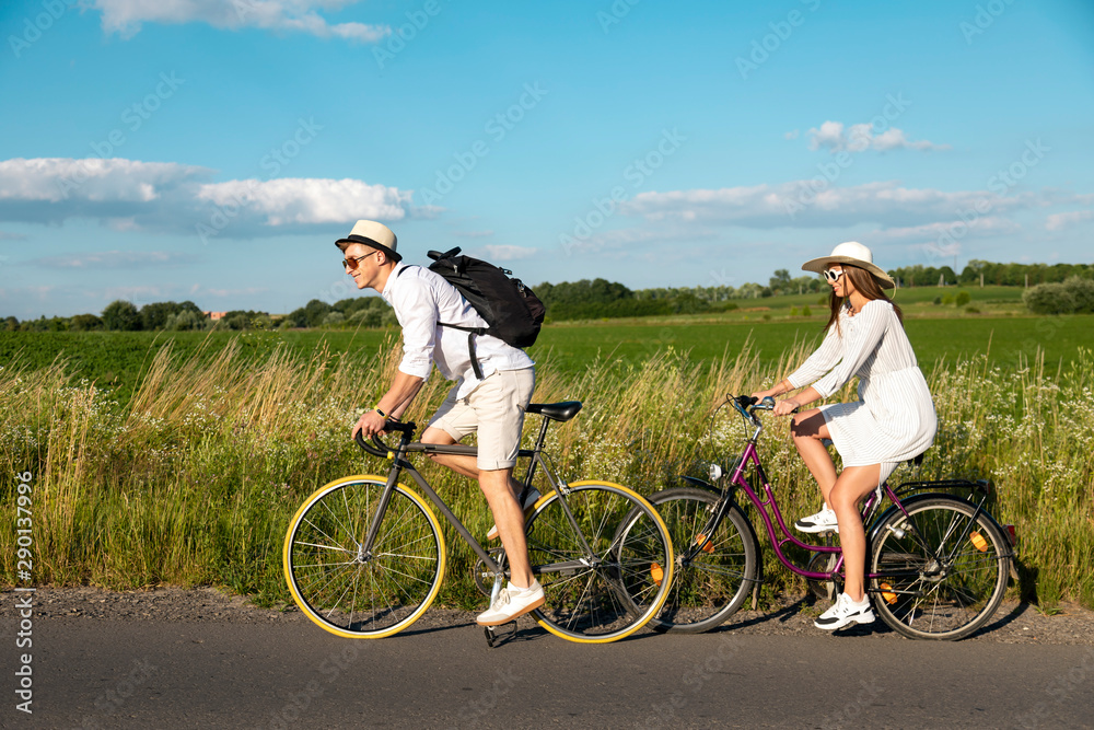 Obraz premium Young sporty couple riding bikes along a rural road