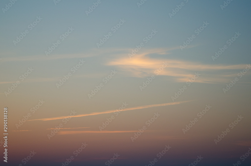 Blue sky with orange clouds and airplane track
