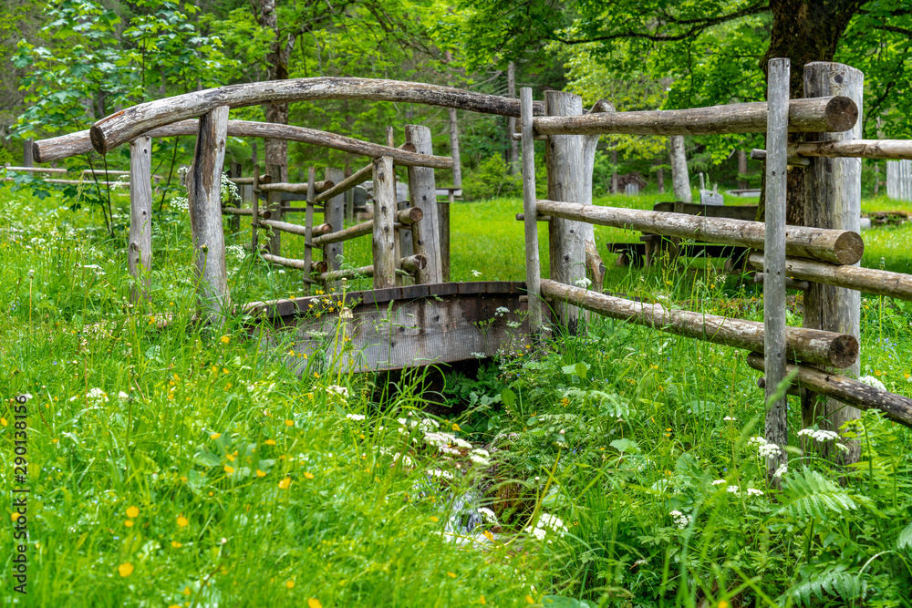 In einem Garten führt eine Holzbrücke über einen Bach In einem Garten führt eine Holzbrücke über einen Bach
