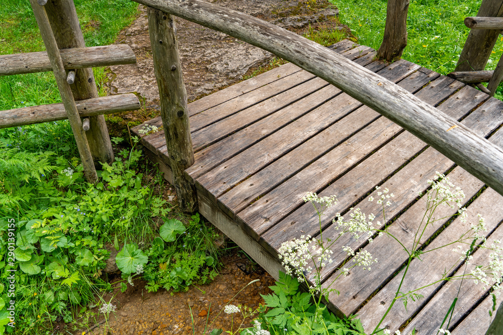 Eine hölzerne Brücke führt über einen Bach