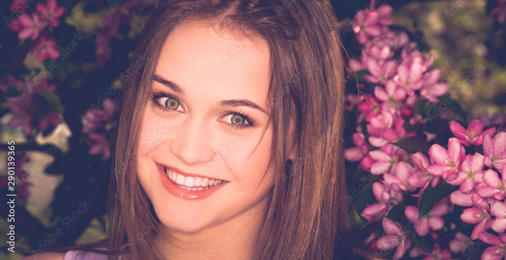 Portrait of young woman in the flowered garden in the spring time. Blossom background. Portrait of young woman in the flowered garden in the spring time. Blossom background.
