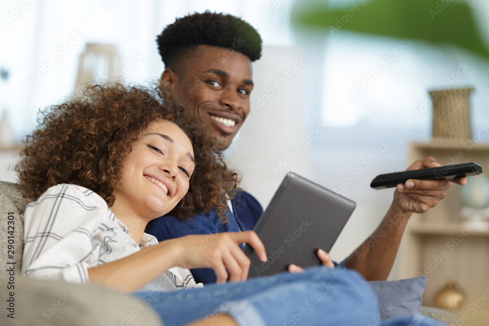 woman using tablet and man watching tv on the sofa