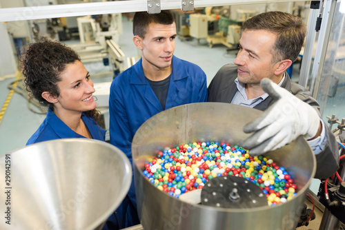 worker showing trainees a hopper full of colorful beads