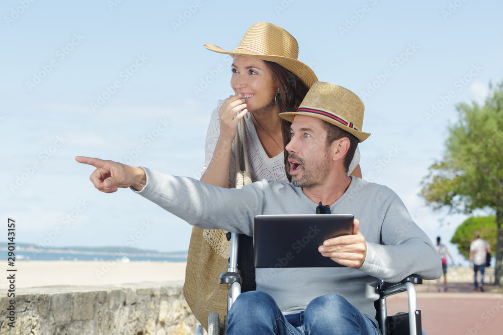 couple at beach disabled man pointing into distance in amazement