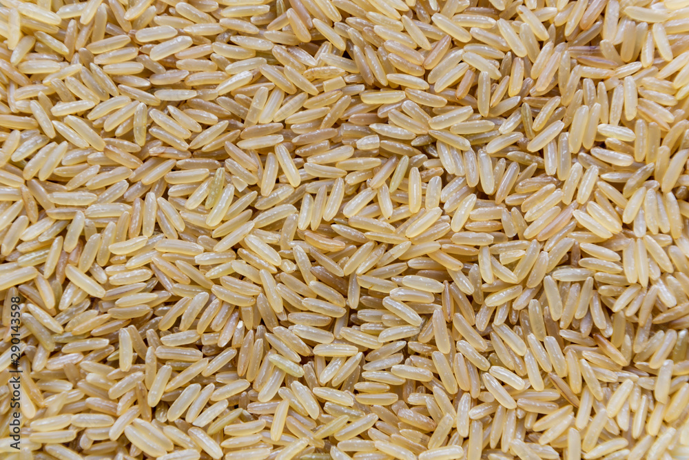 Uncooked raw long brown rice grains background, top view Uncooked raw long brown rice grains background, top view