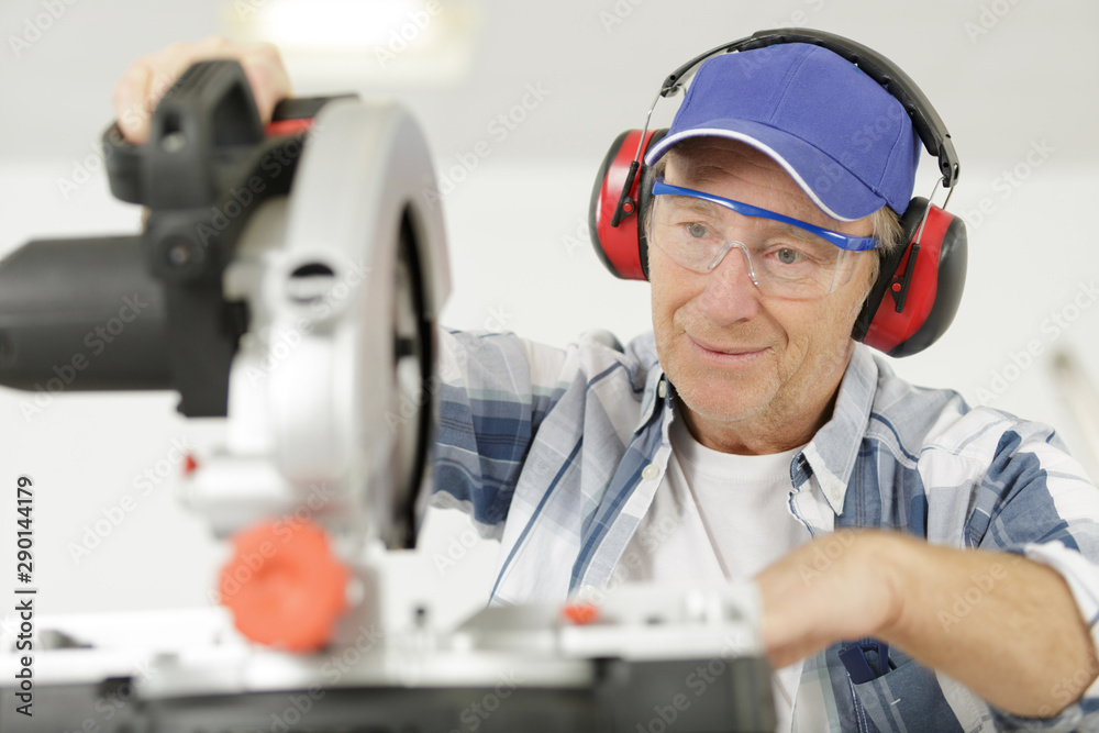 handsome man carpenter using a circular saw handsome man carpenter using a circular saw