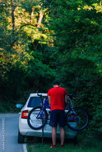 Tired (exhausted) biker puts his bike on a car to get a ride.