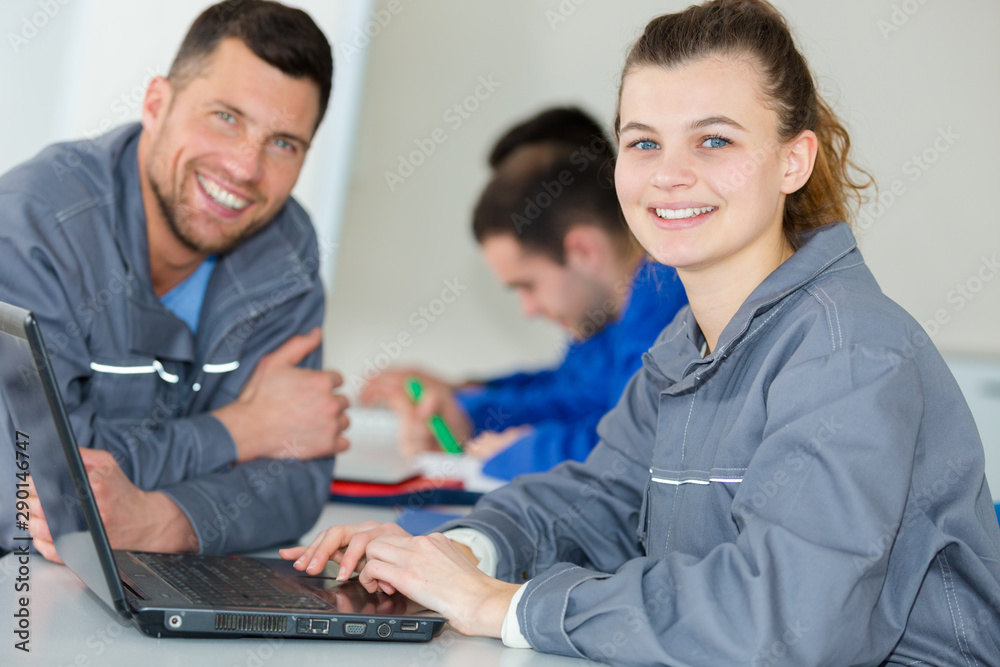 portrait of young woman wearing overalls using laptop portrait of young woman wearing overalls using laptop