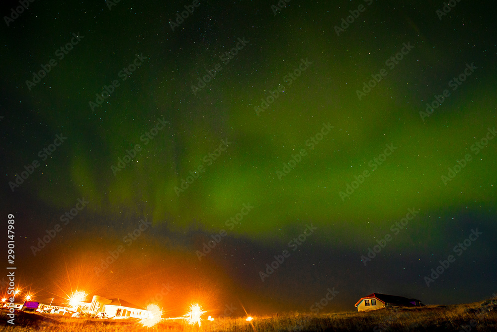 A local town at night from the peninsula below the northern lights in Reykjanes Skaginn. Iceland