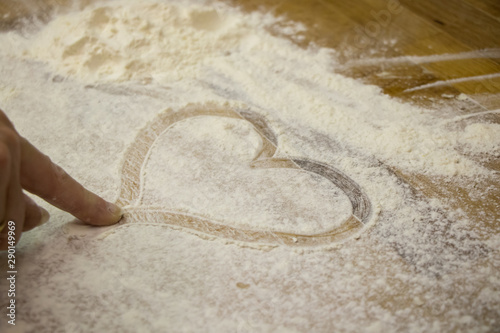 In Mehl gezeichnetes Herz mit Finger