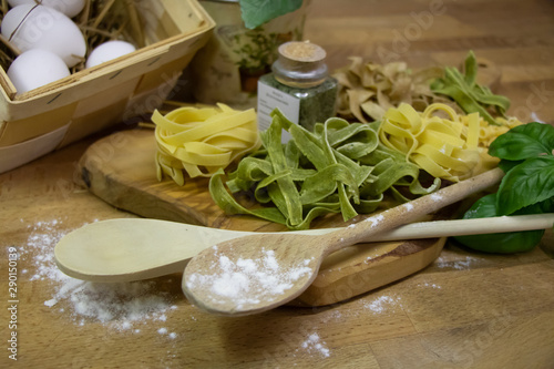 Nudeln auf Brett mit Eiern und Kochlöffeln