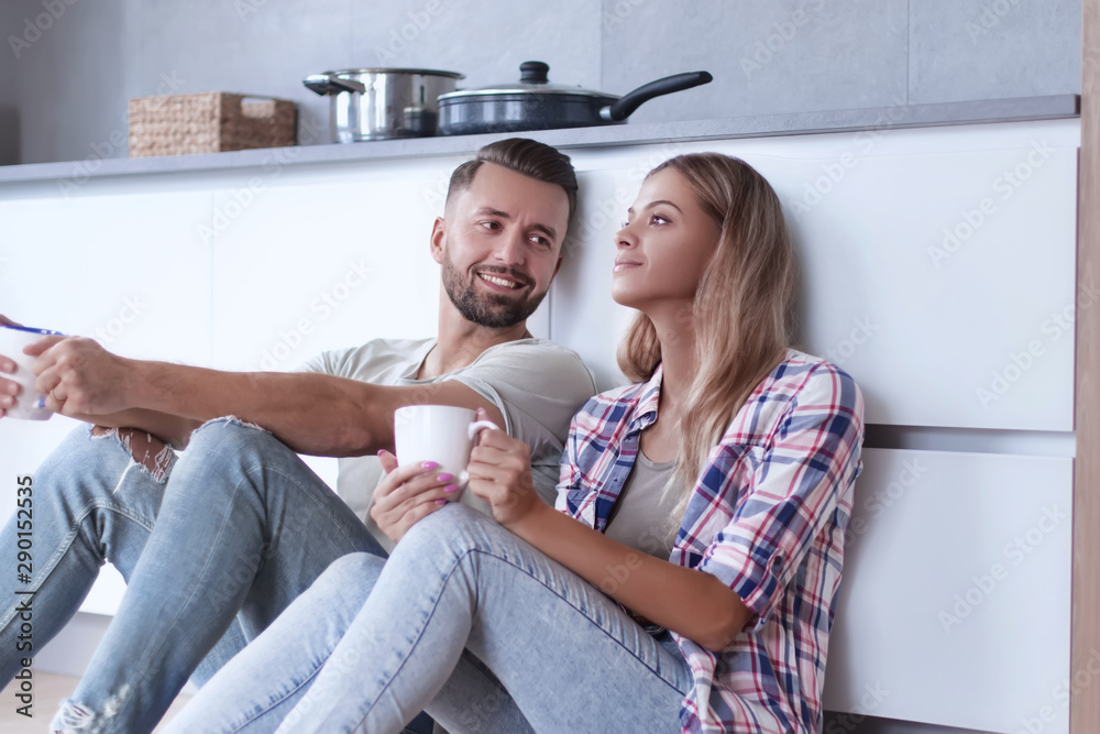 Fototapeta premium young couple drinking coffee sitting on the kitchen floor