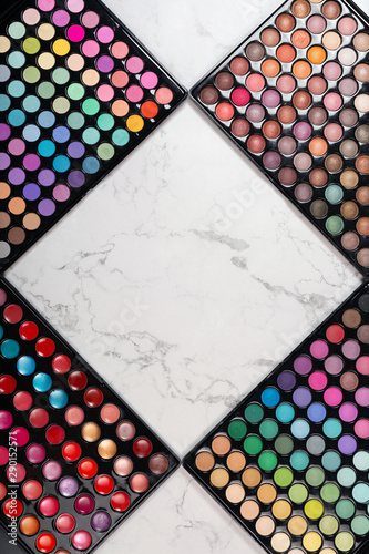 Flat lay of cosmetic eyeshadow palettes on white marble background. Rhombus frame for your copy