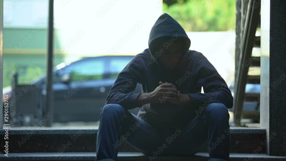 Depressed black boy sitting on stairs contemplating about hard life in ghetto