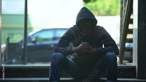 Depressed black boy sitting on stairs contemplating about hard life in ghetto photo