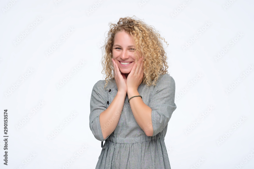 Young blonde curly laughing woman having positive mood. She is given a compliment about her curly hair Young blonde curly laughing woman having positive mood. She is given a compliment about her curly hair