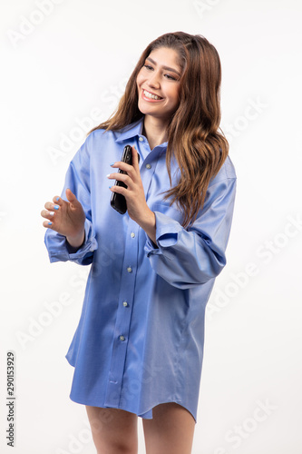 Beautiful Hispanic teen girl holding cell phone and laughing