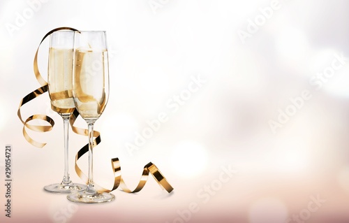 Glasses of champagne with curly ribbon on bright background