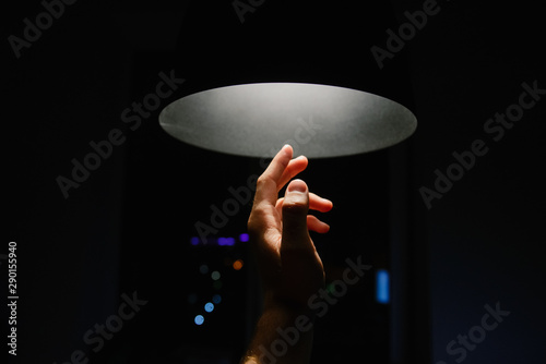 Man's hand reaching towards a ceiling light photo