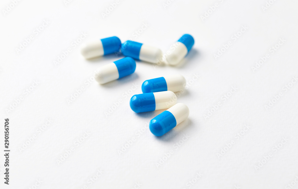 Tri-Creatine capsules. Bodybuilding food supplements on white paper background. Close up. Copy space. 