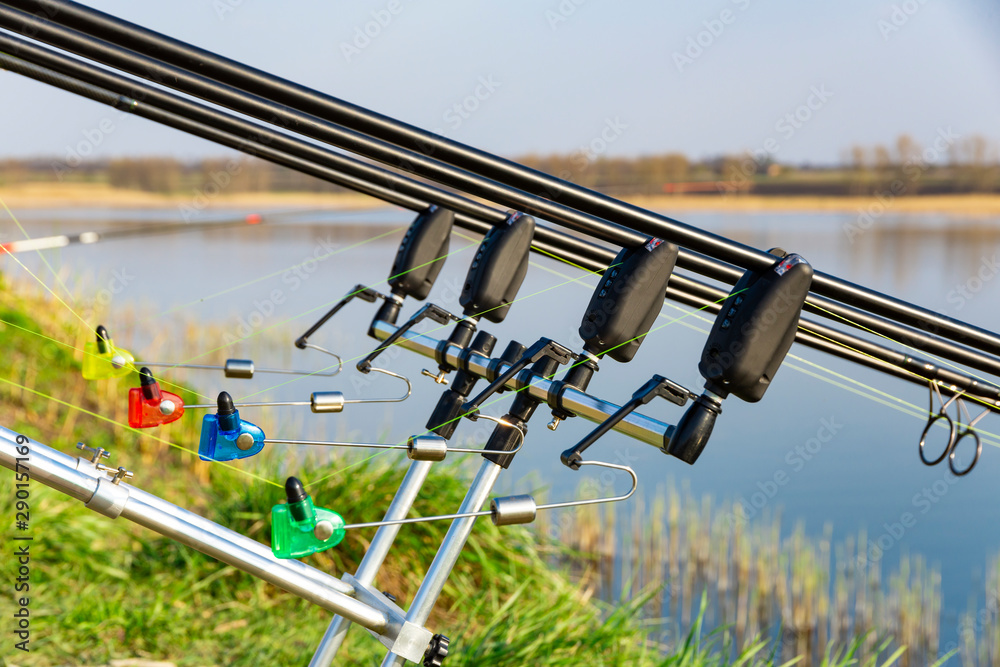 Carp fishing rods with carp bite indicators set up on rod pod near lake  river. Fishing during sunset Stock Photo