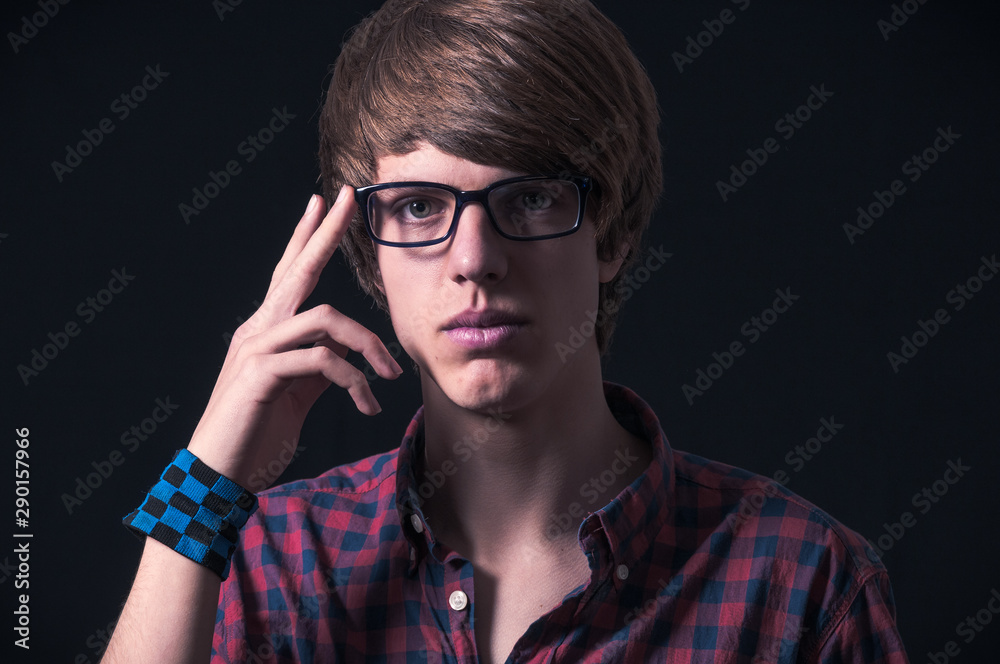 Blond boy with plaid shirt and glasses photographed in studio with black background Blond boy with plaid shirt and glasses photographed in studio with black background