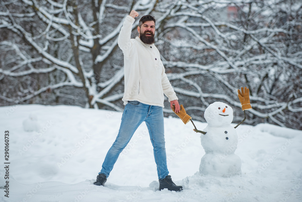 Holly jolly swag Christmas and noel. Happy hipster winter portrait. Snowman. Winter portrait of young handsome hipster in snow Garden make snowman.
