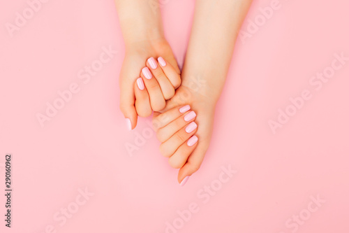 Hands of a beautiful woman on a pink background. Delicate hands with natural manicure, clean skin. Light pink nails.