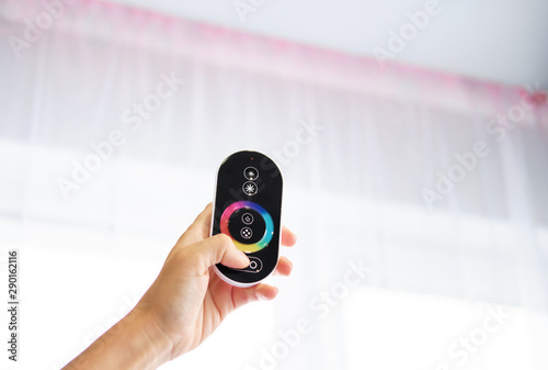 Hand with Remote control on off. LED light Remote Control. LED illumination