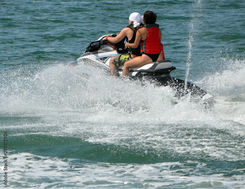 Young couple riding tandem on a speeding jet ski Young couple riding tandem on a speeding jet ski