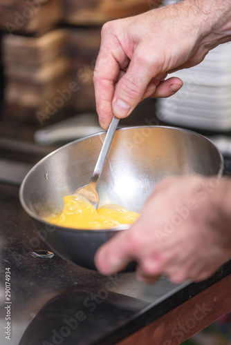 Chef hands beating eggs in a bowl .