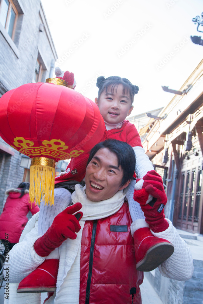 Parent carrying child on shoulders dressed in holiday attire Parent carrying child on shoulders dressed in holiday attire