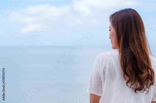 A beautiful asian woman standing back by the sea