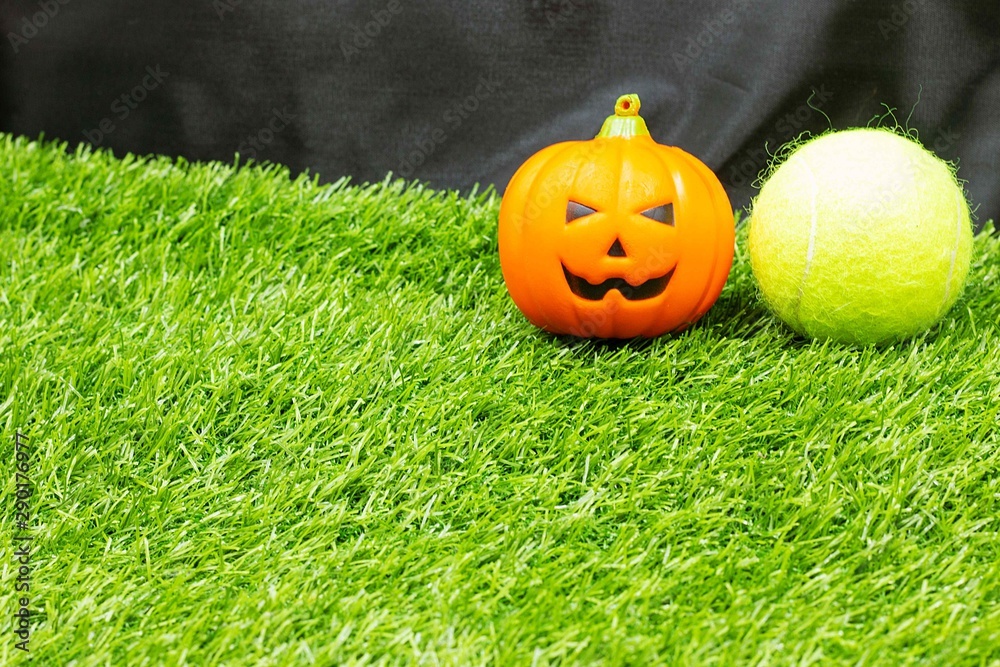 Obraz premium Tennis halloween with tennis ball and pumpkins are on green grass